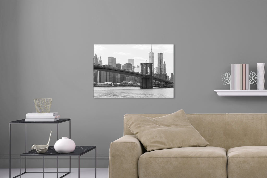 Aufgehängtes Wandbild einer Schwarz-Weiß Fotografie der Brooklyn Bridge mit Blick auf das one world trade center. Fotokunst online kaufen. Hinter Acrylglas oder als Poster