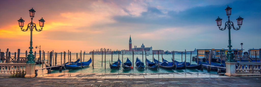 Stadt Fotografie von Gondeln in Venedig bei Sonnenuntergang im Panorama Format. Fotokunst online kaufen. Wandbild hinter Acrylglas oder als Poster