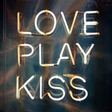 Fotografie einer Typografie Leuchtreklame  mit den Worten Love Play Kiss. Fotokunst und Bilder online kaufen. Wandbild hinter Acrylglas oder als Poster