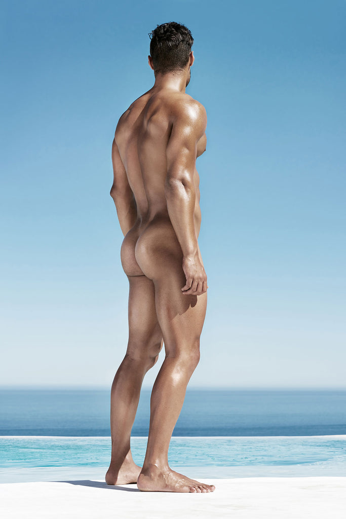 People Fotografie von einem muskulösen nackten Mann von hinten mit Blick aufs Meer im Hochformat. Fotokunst und Bilder online kaufen. Wandbild hinter Acrylglas oder als Poster