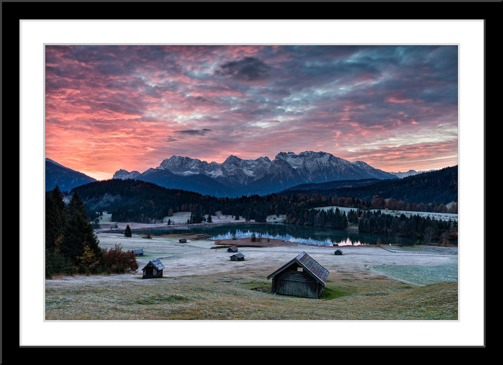 Landschafts Natur Fotografie des Geroldsee bei Sonnenaufgang mit Holzhütten im Vordergrund und den Alpen. Fotokunst und Bilder online kaufen. Wandbild im Rahmen