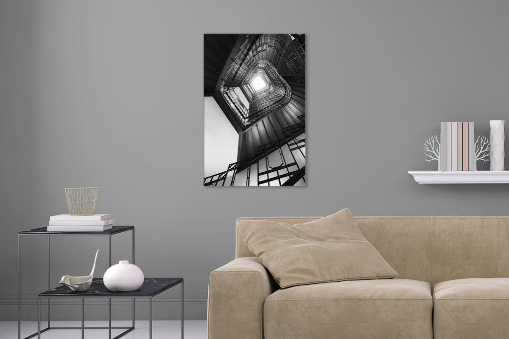 Aufgehängte Schwarz-Weiß Architektur Fotografie von einem Treppenhaus mit Blick nach oben im Hochformat. Fotokunst und Bilder online kaufen. Wandbild hinter Acrylglas oder als Poster