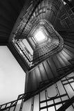 Schwarz-Weiß Architektur Fotografie von einem Treppenhaus mit Blick nach oben im Hochformat. Fotokunst und Bilder online kaufen. Wandbild hinter Acrylglas oder als Poster