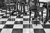 Schwarz-Weiß Fotografie von einem gekachelten Boden mit alten Holz Stühlen. Fotokunst und Bilder online kaufen. Wandbild hinter Acrylglas oder als Poster