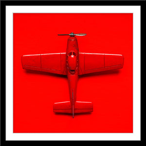 Stilllife Fotografie von einem roten Spielzeug Flugzeug auf rotem Hintergrund im quadratischen Format. Fotokunst und Bilder online kaufen. Wandbild im Rahmen