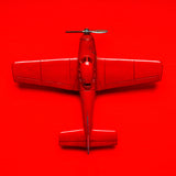 Stilllife Fotografie von einem roten Spielzeug Flugzeug auf rotem Hintergrund im quadratischen Format. Fotokunst und Bilder online kaufen. Wandbild hinter Acrylglas oder als Poster