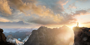 People Landschafts Fotografie von einer Frau die bei Sonnenuntergang auf einer Klippe in den Bergen meditiert im Panorama Format. Fotokunst und Bilder online kaufen. Wandbild hinter Acrylglas oder als Poster