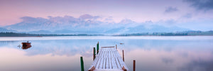 Natur Landschafts Fotografie von einem Steg am See mit einem Boot und Bergen im Hintergrund im Panorama Format. Fotokunst und Bilder online kaufen. Wandbild hinter Acrylglas oder als Poster