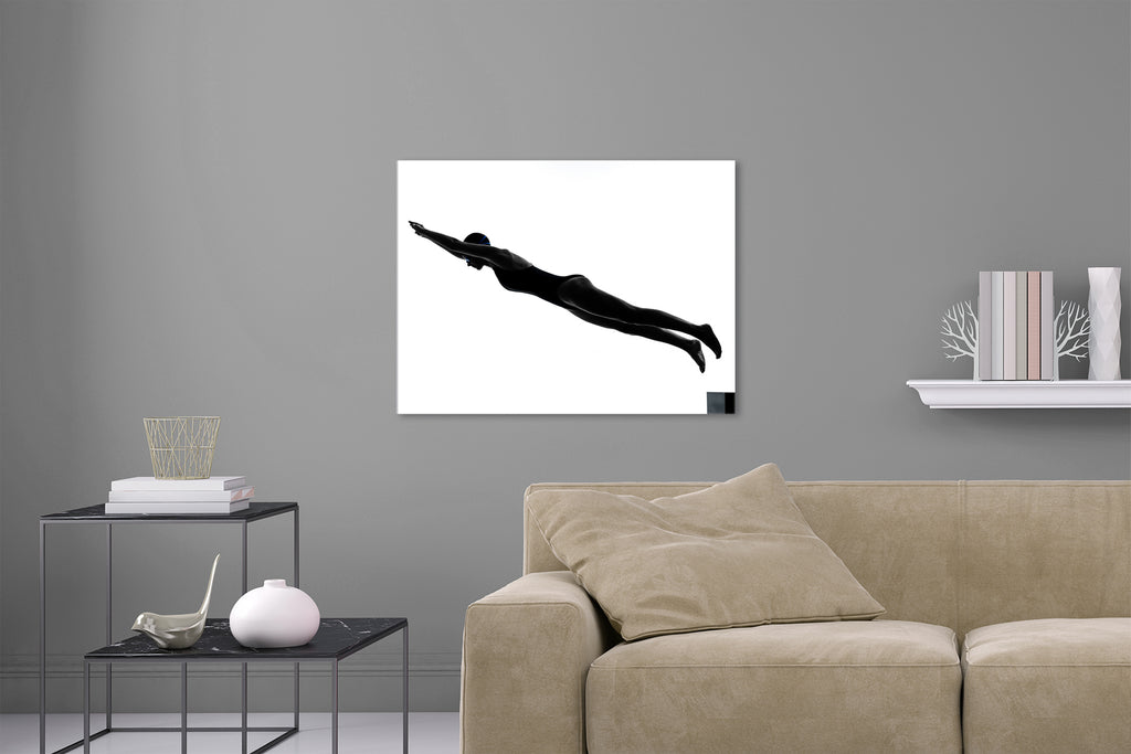 Aufgehängte Schwarz-Weiß People Fotografie von einer Schwimmerin die von einem Startblock spring vor weißem Hintergrund. Fotokunst und Bilder online kaufen. Wandbild hinter Acrylglas oder als Poster