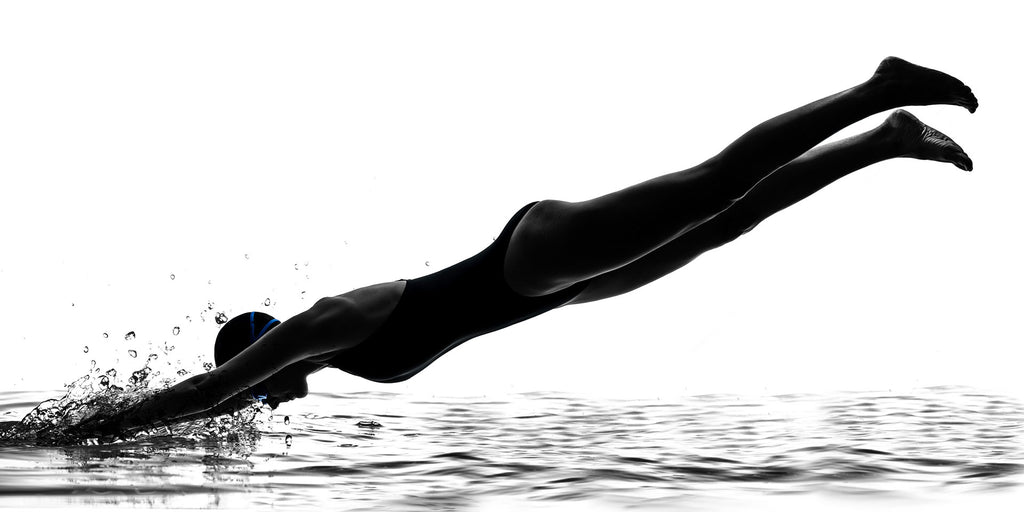 Schwarz-Weiß People Fotografie von einer Schwimmerin die in Wasser eintaucht vor weißem Hintergrund. Fotokunst und Bilder online kaufen. Wandbild hinter Acrylglas oder als Poster