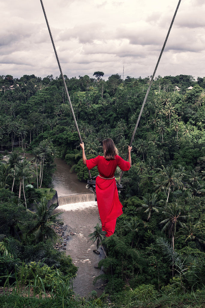 People Natur Fotografie von einer Frau in rotem Kleid auf einer Schaukel vor Dschungel im Hochformat. Fotokunst und Bilder online kaufen. Wandbild hinter Acrylglas oder als Poster