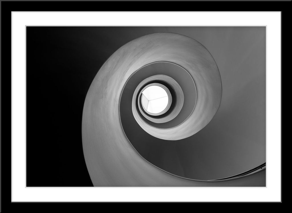 Schwarz-Weiß Architektur Fotografie von einer Wendeltreppe von unten die eine Schnecke bildet. Fotokunst und Bilder online kaufen. Wandbild im Rahmen