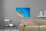 Aufgehängte Fotografie von farbigen, nebeneinander liegenden, Fischerbooten am Strand. Fotokunst online kaufen. Wandbild hinter Acrylglas oder als Poster
